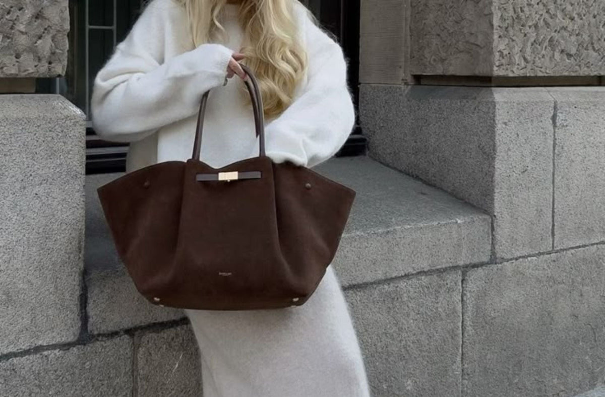 A woman in white sweater wears a brown tote bag