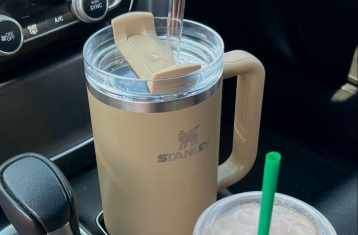 beige stanley cup and starbucks coffee in car cup holder 